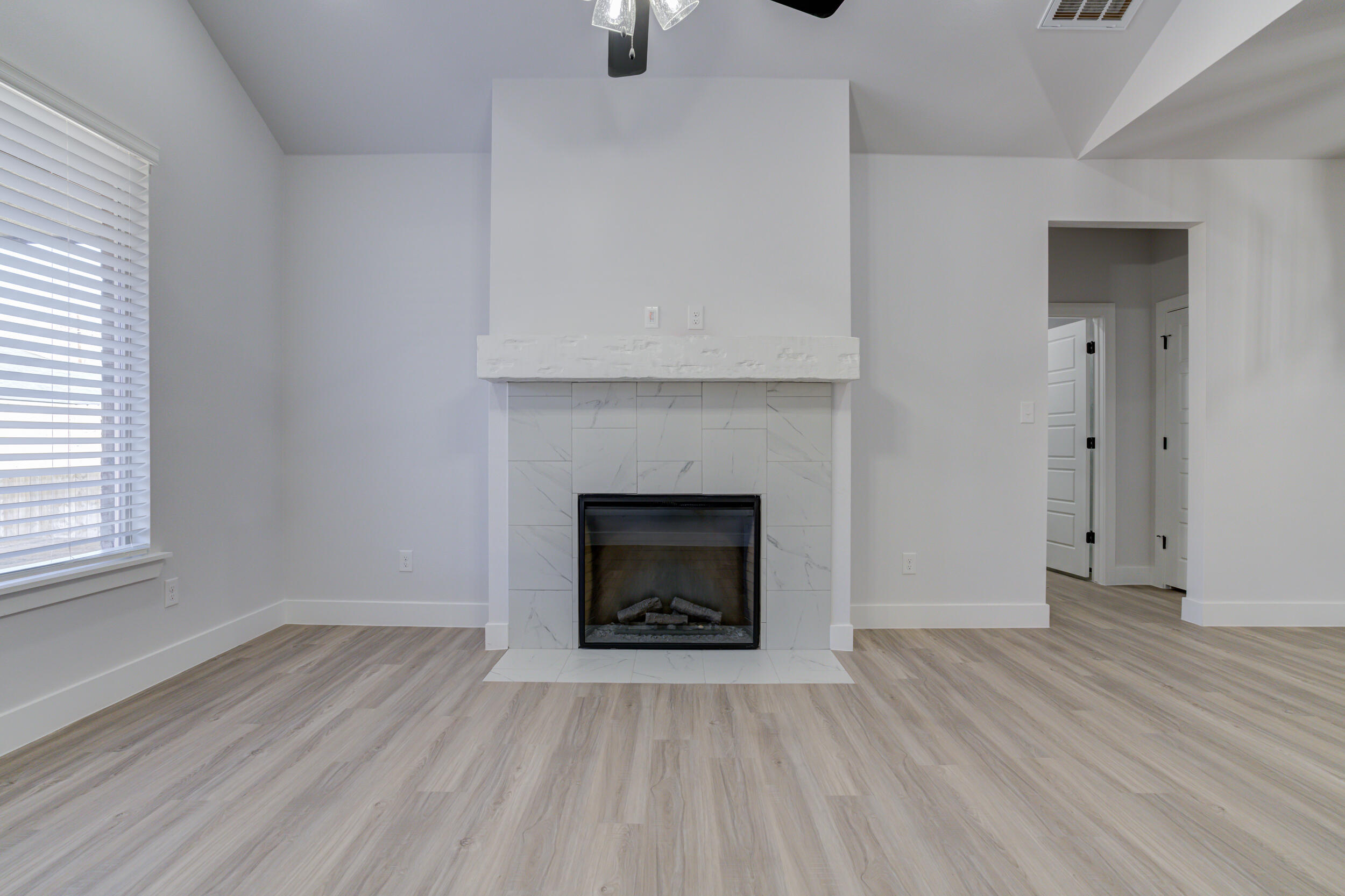 5808 Viola Avenue Lubbock, TX 79407 - Photo 31 of 60 an empty room with wooden floor fireplace and windows