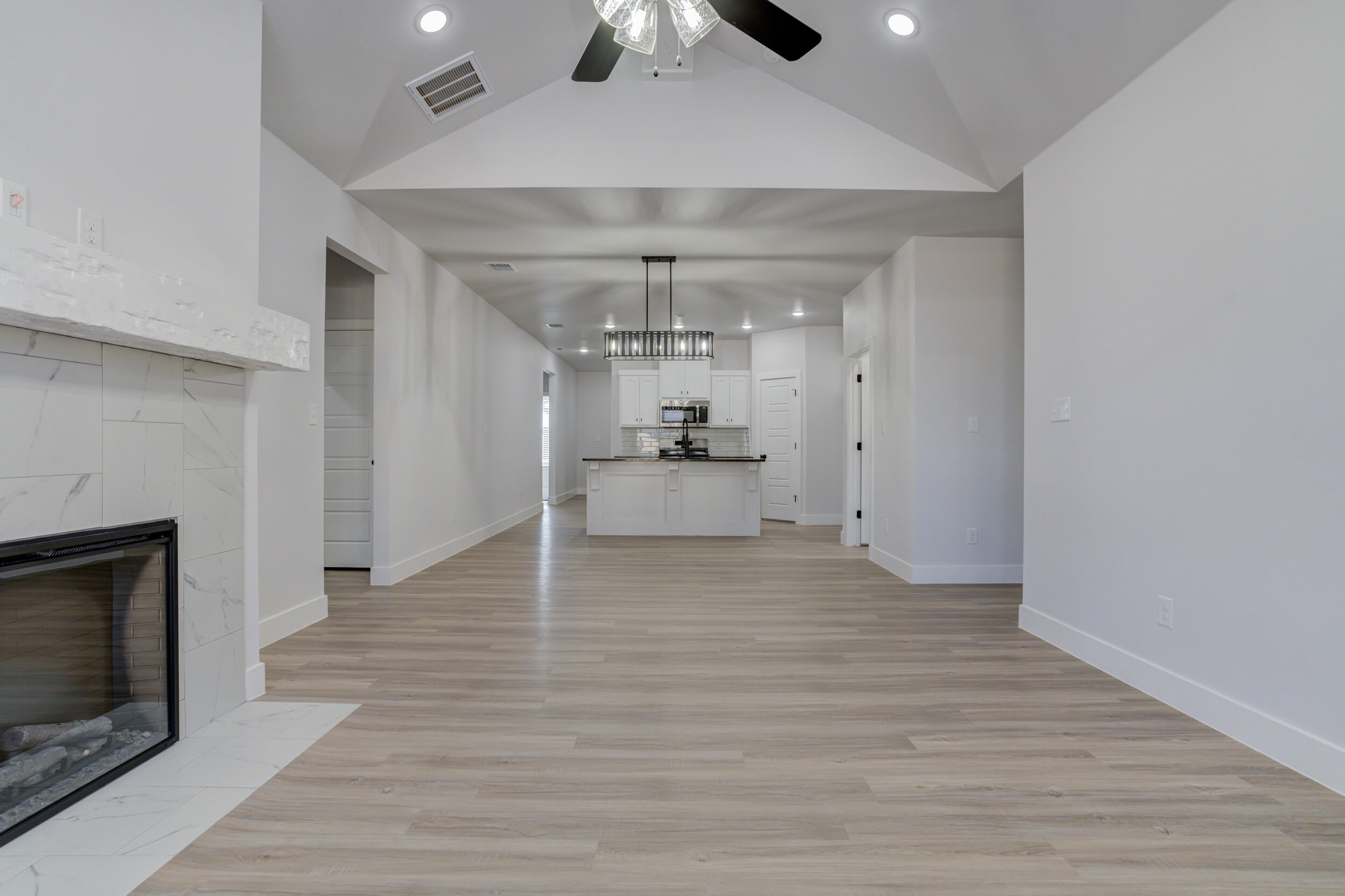 5808 Viola Avenue Lubbock, TX 79407 - Photo 33 of 60 an empty room with wooden floor fireplace and chandelier fan