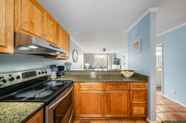 a kitchen with kitchen island granite countertop wooden cabinets and a stove