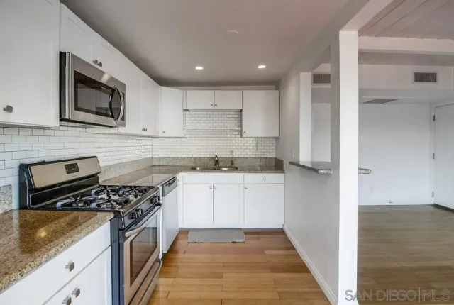 a kitchen with stainless steel appliances granite countertop a stove a sink and a microwave