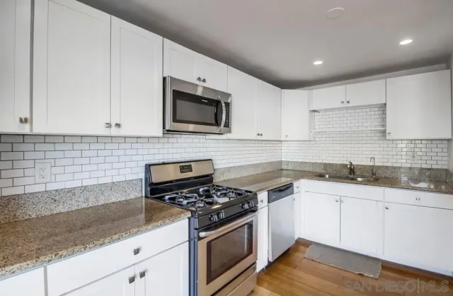 a kitchen with granite countertop cabinets stainless steel appliances and a sink