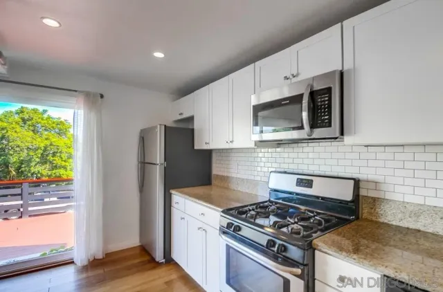 a kitchen with stainless steel appliances granite countertop white cabinets and black stove top oven