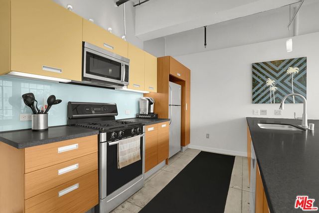 a kitchen with stainless steel appliances granite countertop a stove a sink and a microwave