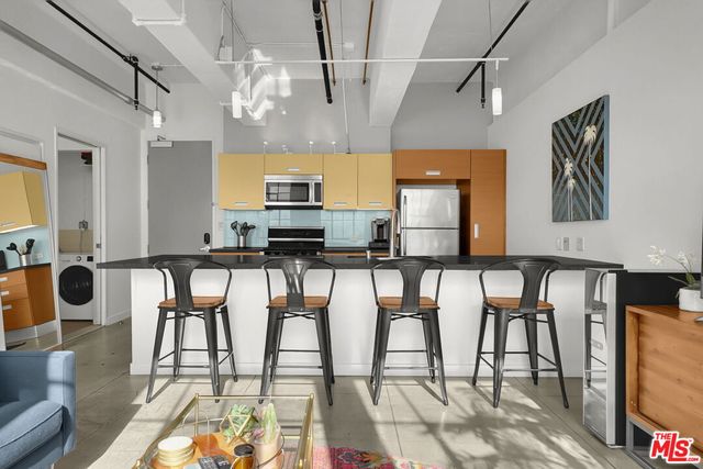 a kitchen with stainless steel appliances kitchen island granite countertop a table chairs and a refrigerator