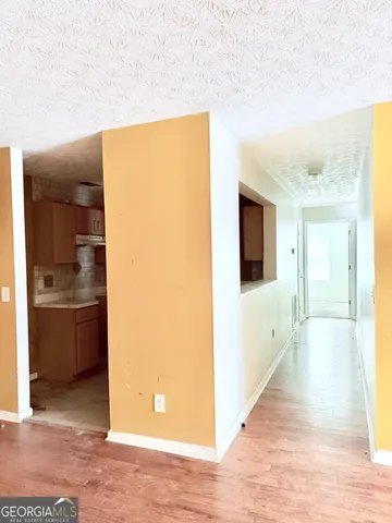 a view of a hallway with wooden floor and a living room