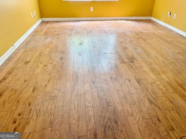 a view of empty room with wooden floor