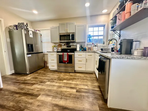 a kitchen with stainless steel appliances granite countertop a refrigerator sink stove microwave and cabinets