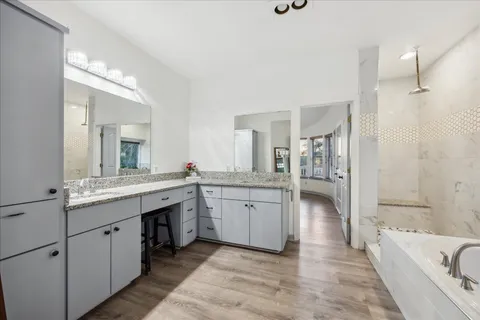 a bathroom with a granite countertop double vanity sink a mirror and a bathtub