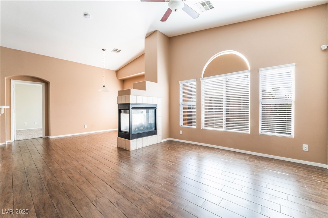 1570 Rusty Ridge Lane Henderson, NV 89002 - Photo 13 of 35 Unfurnished living room with visible vents, ceiling fan, wood finished floors, and a fireplace