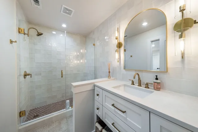 a bathroom with a sink shower and a mirror