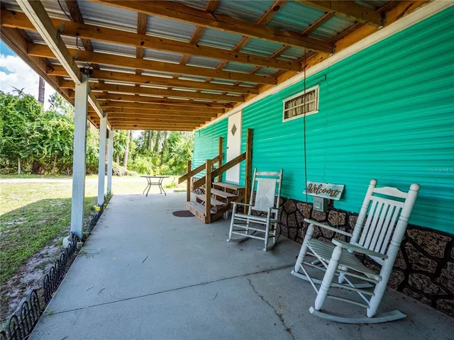 a view of a patio with table and chairs under an umbrella with a barbeque grill