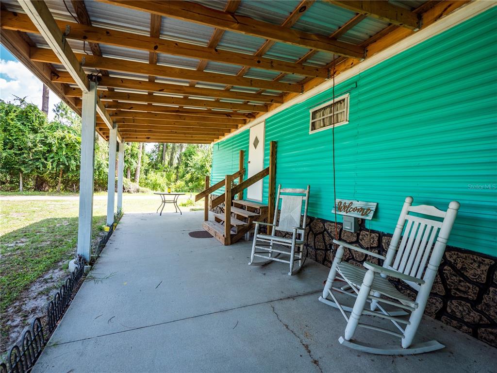 23673 Northeast 134th Lane Road Fort McCoy, FL 32134 - Photo 5 of 34 a view of a patio with table and chairs under an umbrella with a barbeque grill