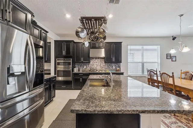 a kitchen with stainless steel appliances granite countertop a sink a stove and a wooden floors