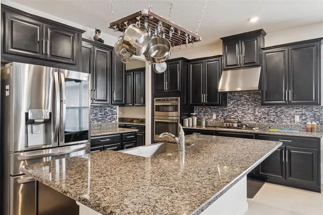 a kitchen with kitchen island granite countertop a sink refrigerator and cabinets