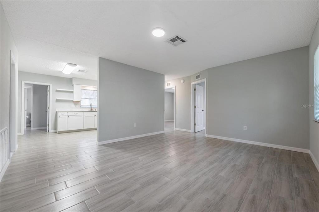 7802 Butler Avenue Hudson, FL 34667 - Photo 3 of 30 a view of an empty room with wooden floor and kitchen