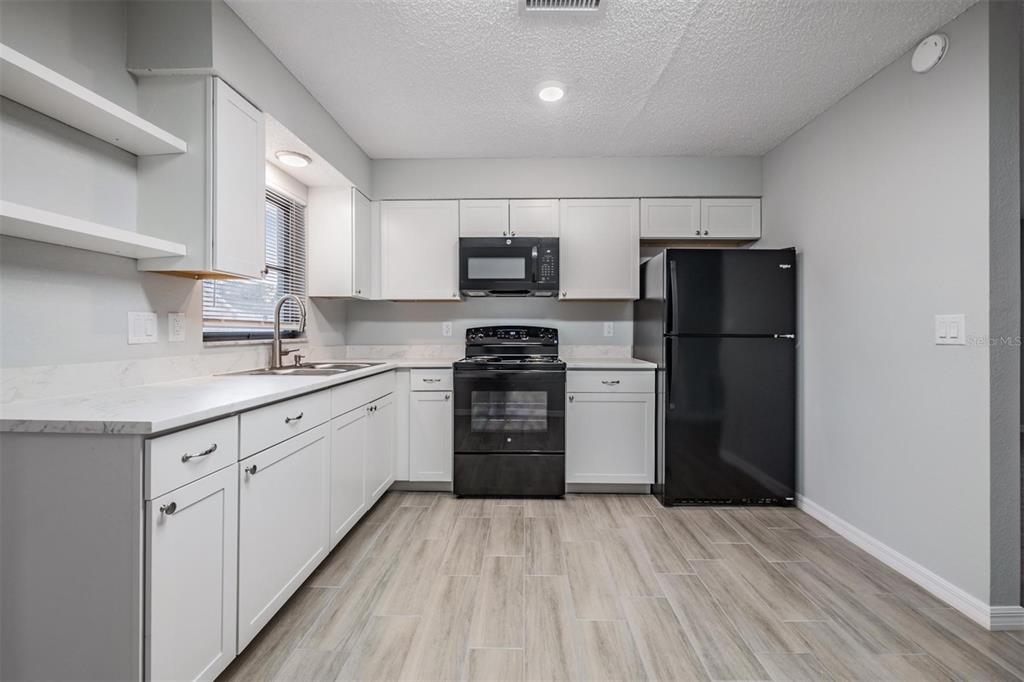 7802 Butler Avenue Hudson, FL 34667 - Photo 5 of 30 a kitchen with a refrigerator and a stove top oven