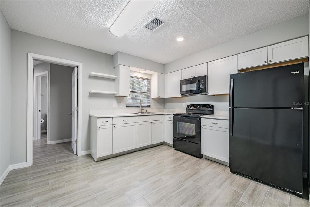 7802 Butler Avenue Hudson, FL 34667 - Photo 7 of 30 a kitchen with a refrigerator stove and wooden cabinets
