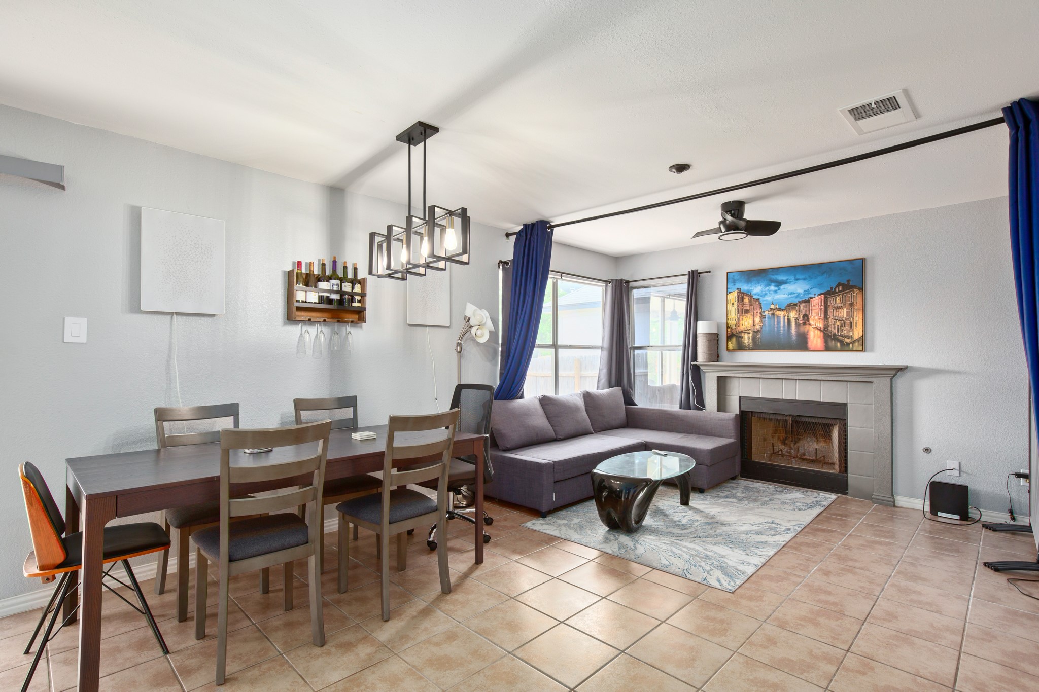 13803 Randalstone Drive Pflugerville, TX 78660 - Photo 15 of 27 Living room with a tile fireplace, light tile patterned flooring, a ceiling fan, and a chandelier