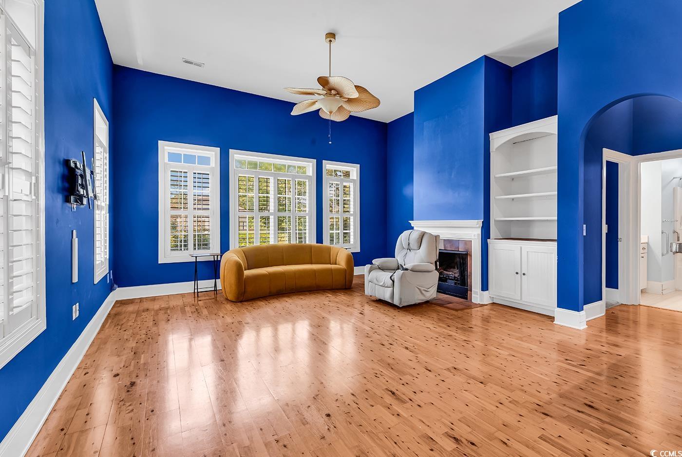 553 Linton Park Road Myrtle Beach, SC 29579 - Photo 14 of 40 Sitting room with a tiled fireplace, hardwood / wood-style floors, a ceiling fan, built in shelves, and arched walkways