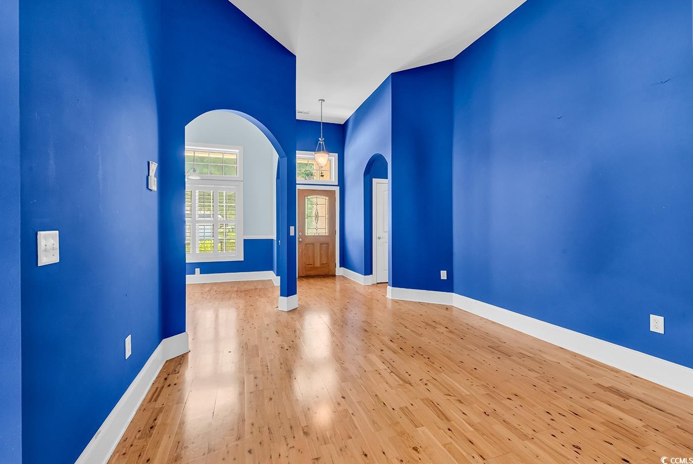 553 Linton Park Road Myrtle Beach, SC 29579 - Photo 5 of 40 Unfurnished room with arched walkways, hardwood / wood-style flooring, and a high ceiling