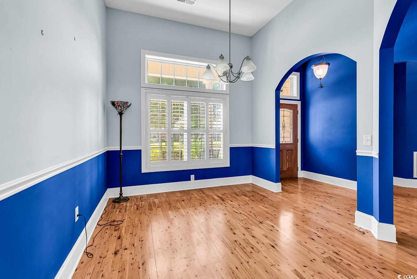 553 Linton Park Road Myrtle Beach, SC 29579 - Photo 8 of 40 Unfurnished dining area featuring arched walkways, hardwood / wood-style flooring, a chandelier, and a high ceiling