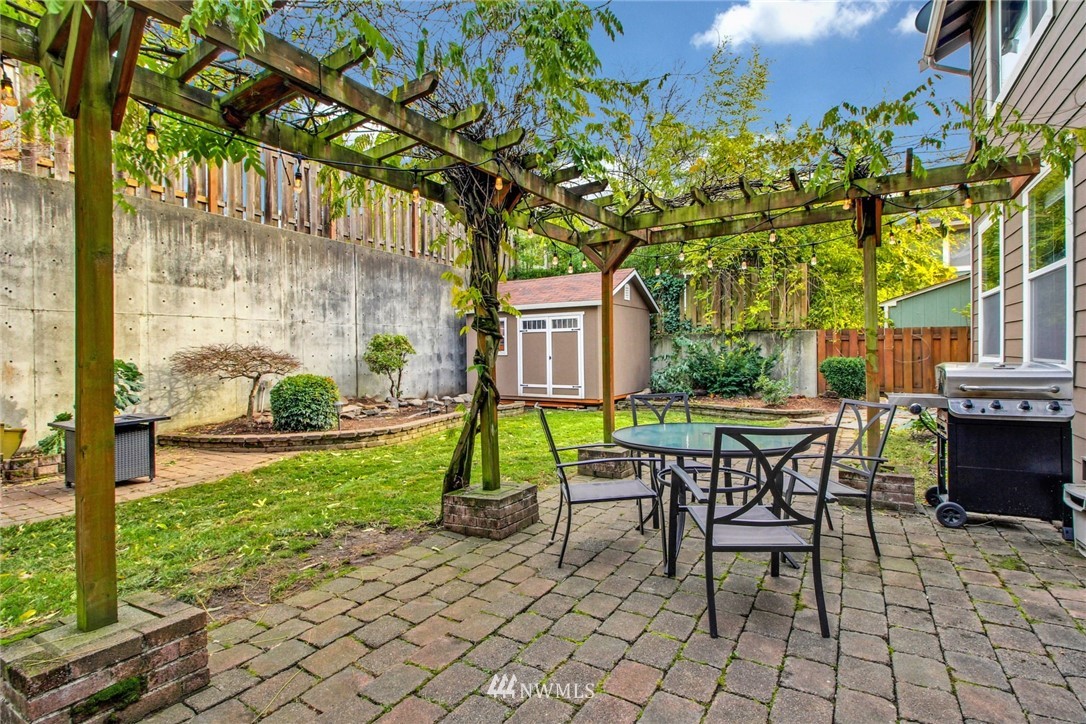 27752 Maple Ridge Way Southeast Maple Valley, WA 98038 - Photo 24 of 25 a view of a backyard with table and chairs and a barbeque with potted plants and large trees