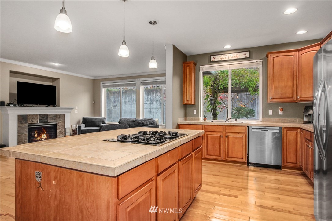 27752 Maple Ridge Way Southeast Maple Valley, WA 98038 - Photo 6 of 25 a kitchen with stainless steel appliances granite countertop a stove a sink dishwasher a refrigerator with a dining table and chairs with wooden floor