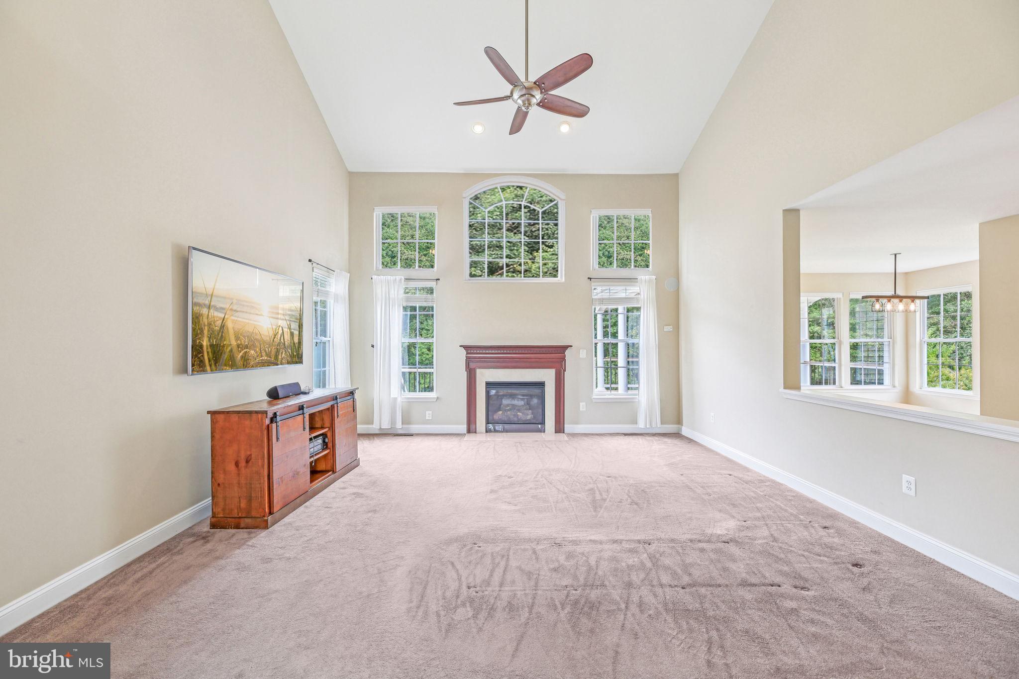 705 Jaclyn Circle Freeland, MD 21053 - Photo 8 of 45 an empty room with windows a fireplace and a chandelier fan