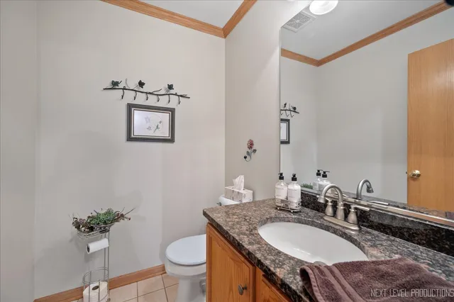 a bath room with a granite countertop toilet a sink and a mirror