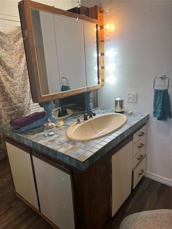 1516 South 8th Street Chillicothe, TX 79225 - Photo 20 of 28 a bathroom with a granite countertop sink and a mirror