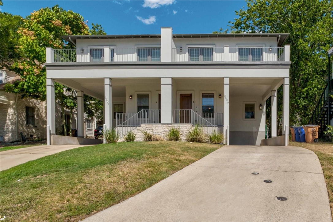 a view of a white house with a small yard plants and large tree