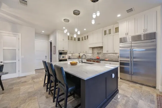 a kitchen with kitchen island granite countertop a sink a center island stainless steel appliances and cabinets