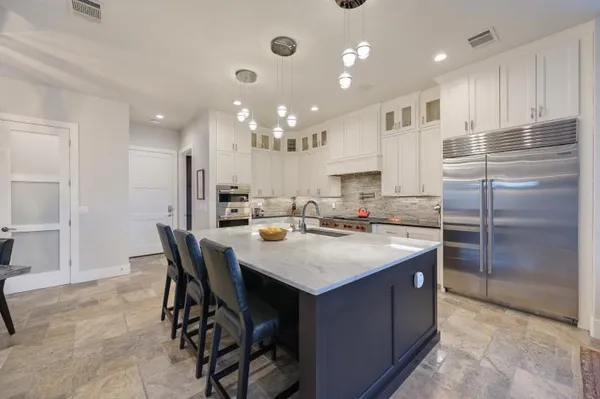 a kitchen with kitchen island granite countertop a sink a center island stainless steel appliances and cabinets