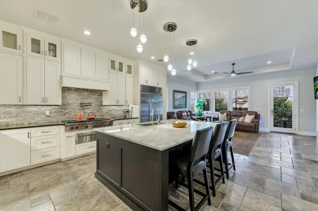 a kitchen with stainless steel appliances granite countertop table chairs sink and cabinets