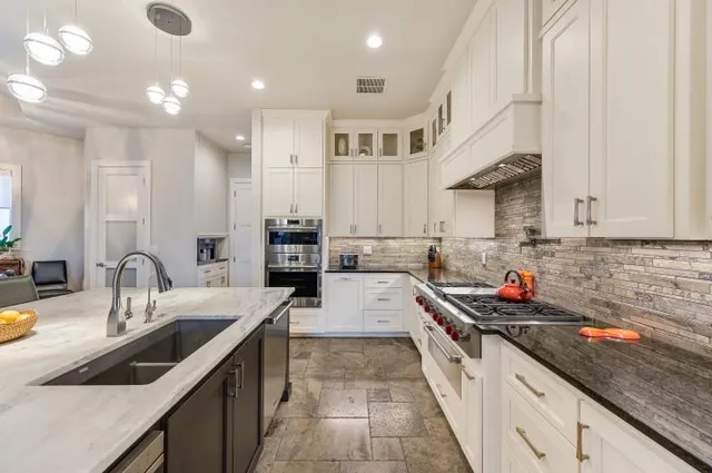 a large kitchen with stainless steel appliances granite countertop a sink stove and cabinets