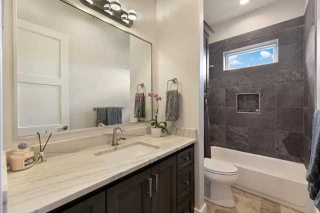 a bathroom with a granite countertop sink a toilet and shower