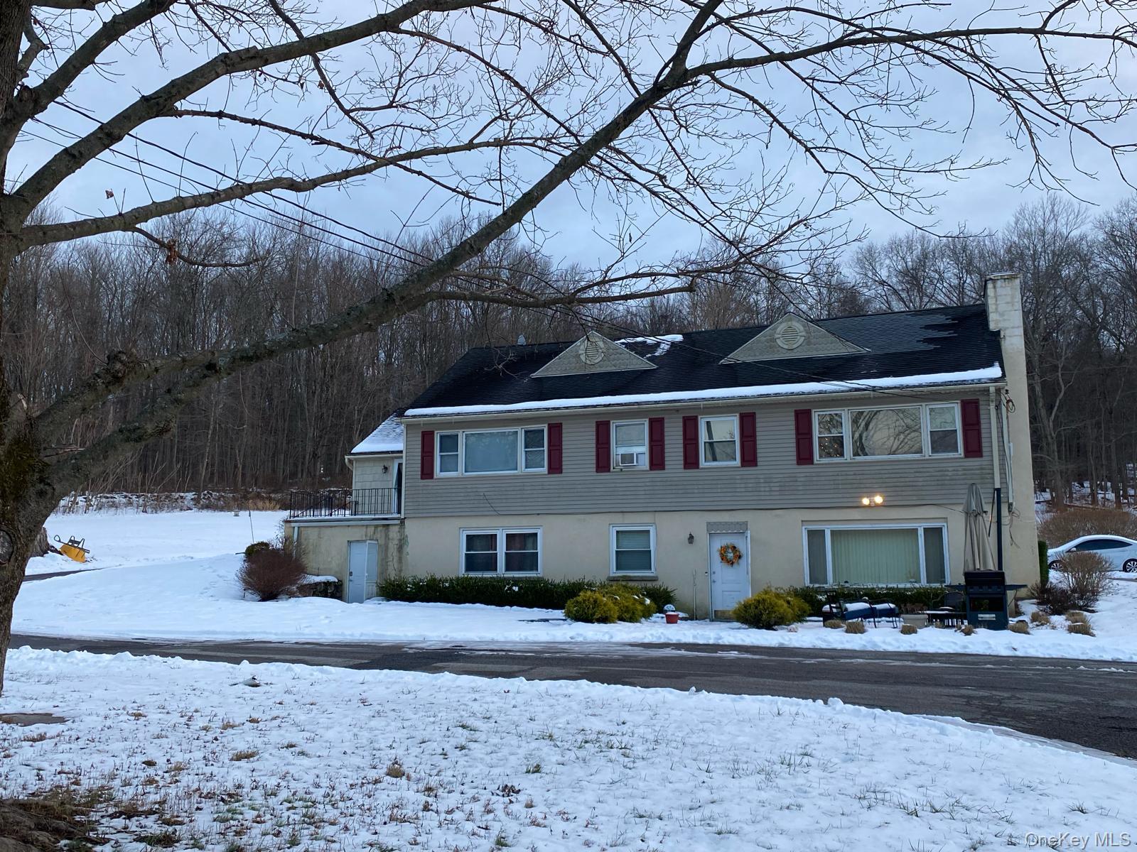 View of front of house with a chimney, a balcony, and a wooded view