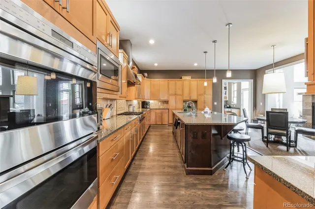 a large kitchen with stainless steel appliances kitchen island granite countertop a large kitchen island a stove a sink a dining table and chairs