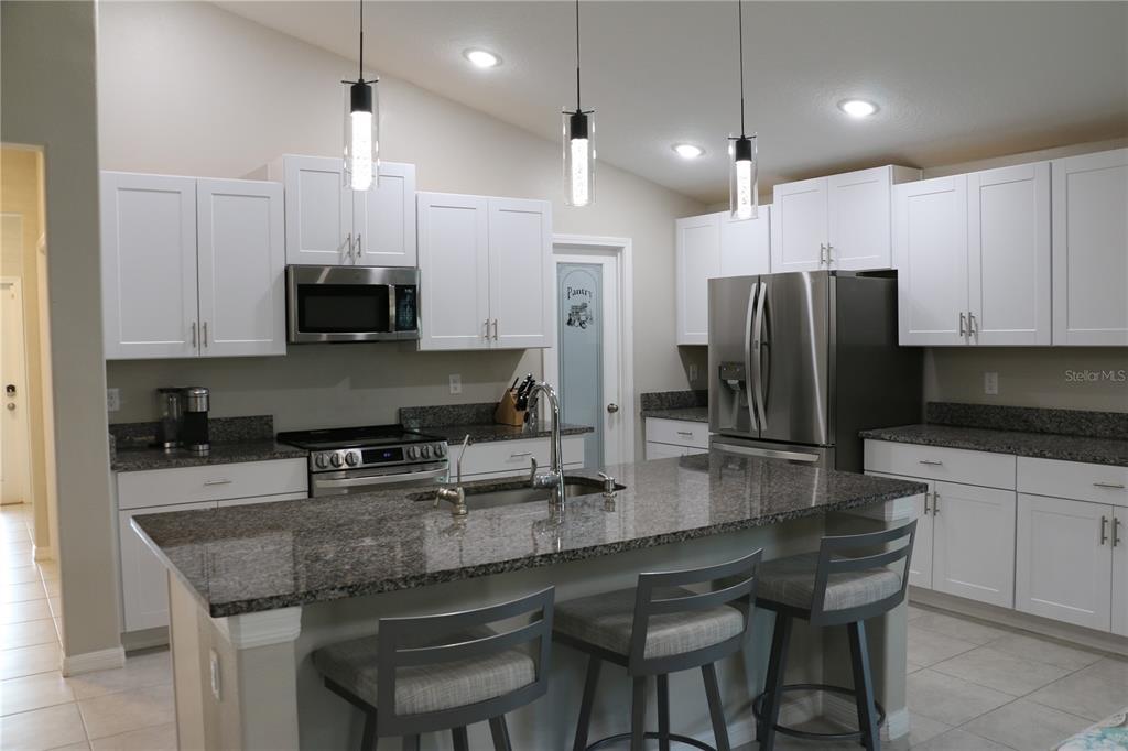 16554 Delia Street Wimauma, FL 33598 - Photo 12 of 44 a kitchen with stainless steel appliances granite countertop a sink a stove a refrigerator a center island and chairs