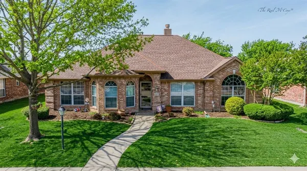 a front view of a house with garden and trees