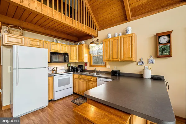 a kitchen with a refrigerator a stove a sink dishwasher and white cabinets with wooden floor