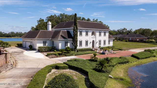 a front view of a house with a yard and lake view