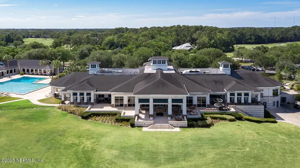 an aerial view of a house with swimming pool and green yard