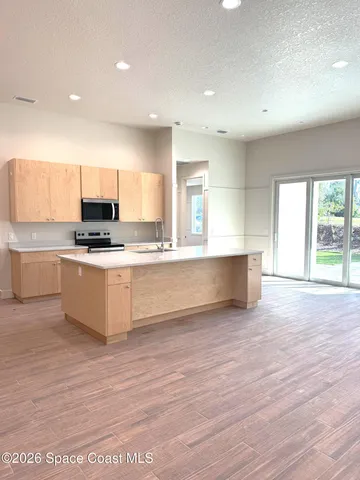 a large kitchen with stainless steel appliances a large counter top a stove and a refrigerator