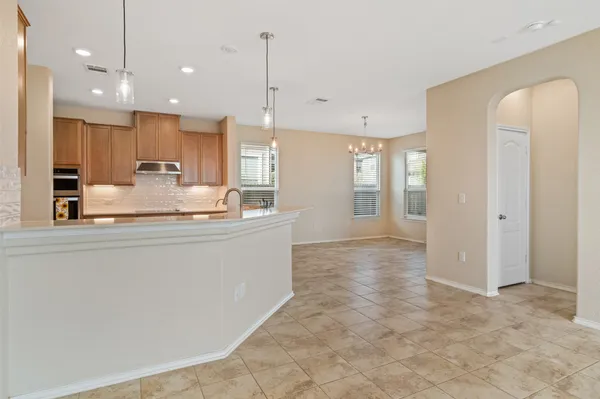 a large kitchen with kitchen island a stove a refrigerator a sink and white cabinets with wooden floor