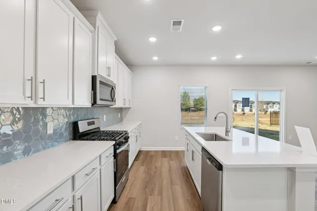 a kitchen with a sink a refrigerator and white cabinets