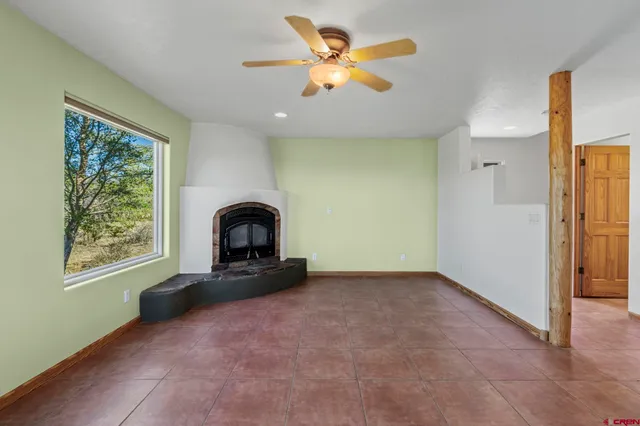 an empty room with windows and fireplace