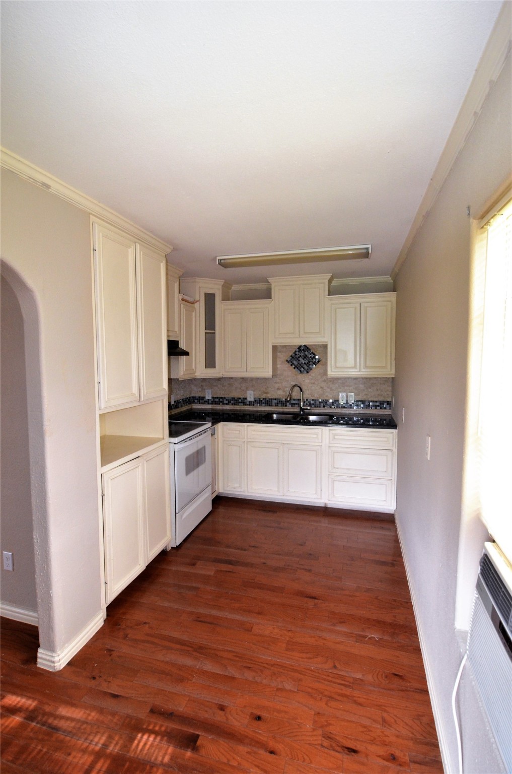 7326 Eagle Pass Street Houston, TX 77020 - Photo 9 of 26 a large white kitchen with granite countertop a stove top oven a sink and white cabinets with wooden floor