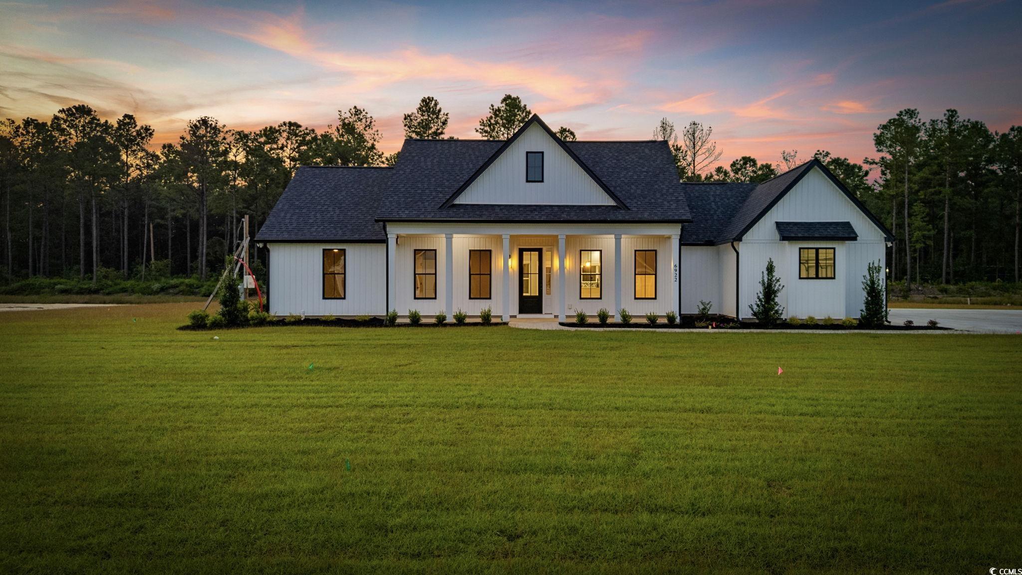 Modern inspired farmhouse featuring a porch, a front yard, and a shingled roof