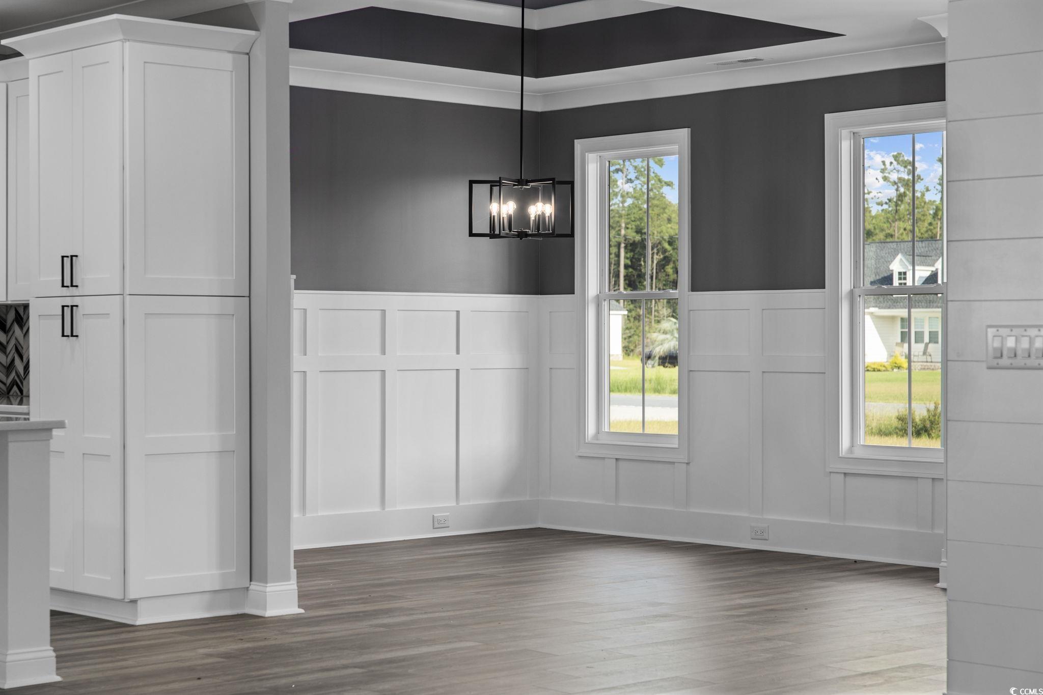 6922 Pauley Swamp Road Conway, SC 29527 - Photo 23 of 40 Unfurnished dining area with a decorative wall, wainscoting, dark wood-type flooring, and a chandelier